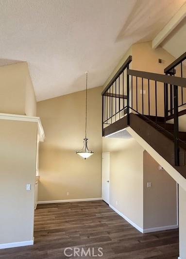 interior space featuring wood finished floors, high vaulted ceiling, baseboards, and beamed ceiling