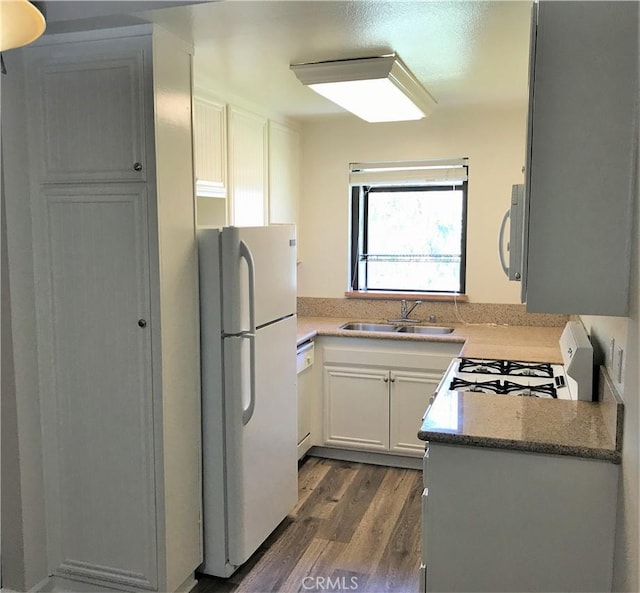 kitchen featuring white appliances, a sink, dark wood-type flooring, white cabinets, and light stone countertops