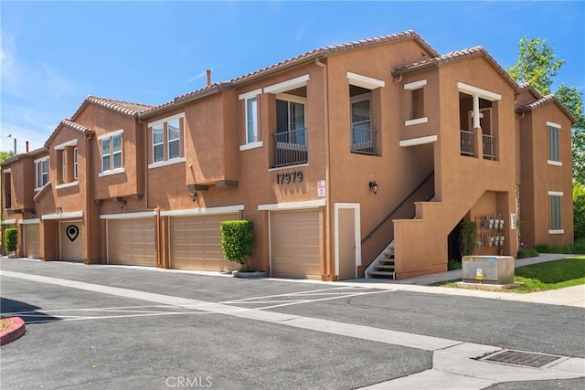 17979 Lost Canyon Rd Unit 104, Canyon Country, CA 91387 - townhome / multi-family property featuring a garage, stairs, stucco siding, and a tile roof