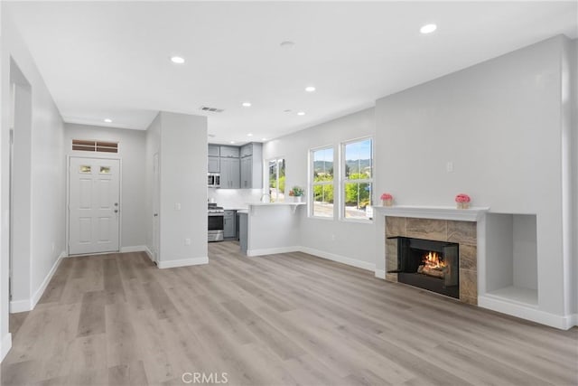 17979 Lost Canyon Rd Unit 104, Canyon Country, CA 91387 - unfurnished living room featuring light wood-type flooring, recessed lighting, a tile fireplace, and baseboards