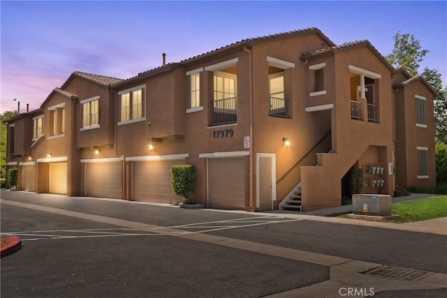 17979 Lost Canyon Rd Unit 104, Canyon Country, CA 91387 - view of property with a garage, stucco siding, stairway, and asphalt driveway