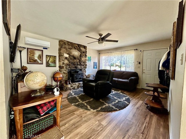 living room with a wall unit AC, wood finished floors, and ceiling fan