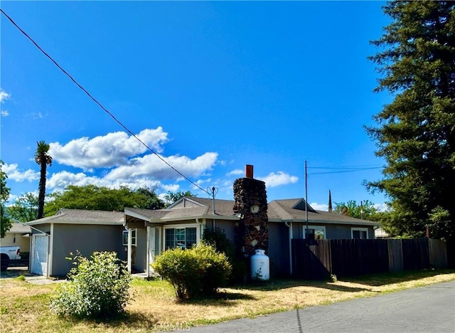 ranch-style house featuring fence, a chimney, stucco siding, and an attached garage
