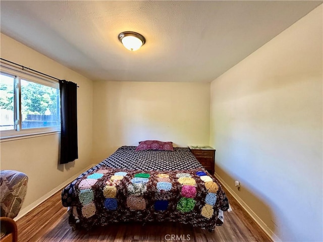 bedroom featuring wood finished floors and baseboards