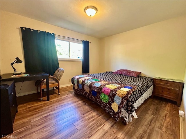 bedroom with wood finished floors and baseboards