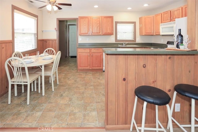 433 Conklin Rd, Big Bear Lake, CA 92315 - kitchen featuring white microwave, wainscoting, ceiling fan, a kitchen breakfast bar, and a peninsula
