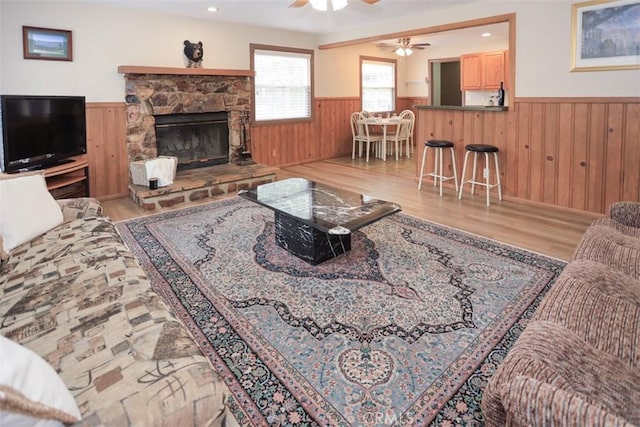 433 Conklin Rd, Big Bear Lake, CA 92315 - living area featuring a wainscoted wall, wooden walls, wood finished floors, a ceiling fan, and a stone fireplace