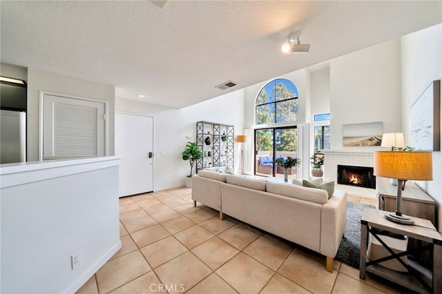 5145 Tortuga Dr Unit 209, Huntington Beach, CA 92649 - living area with light tile patterned flooring, a brick fireplace, and a textured ceiling
