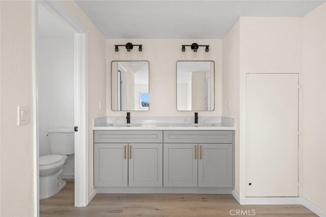 2134 Via Puerta Unit O, Laguna Woods, CA 92637 - bathroom with toilet, double vanity, wood finished floors, and baseboards