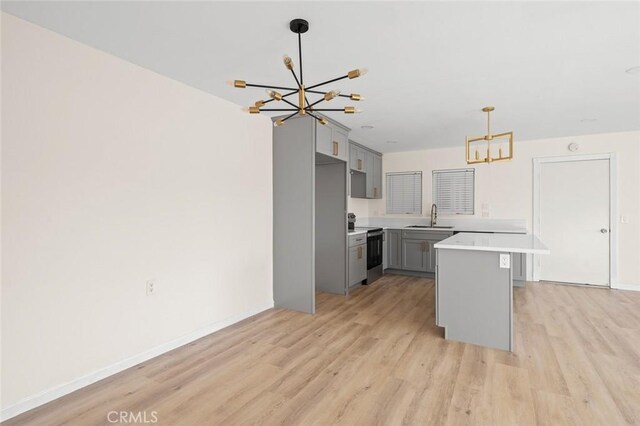 2134 Via Puerta Unit O, Laguna Woods, CA 92637 - kitchen with a chandelier, a sink, electric range oven, gray cabinetry, and light wood finished floors