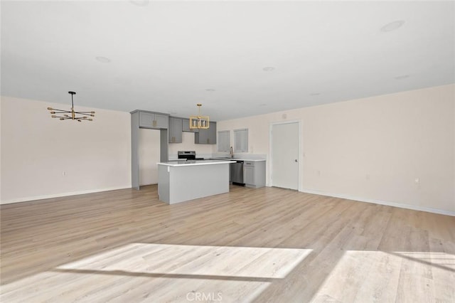 2134 Via Puerta Unit O, Laguna Woods, CA 92637 - unfurnished living room with a chandelier, light wood-type flooring, baseboards, and a sink