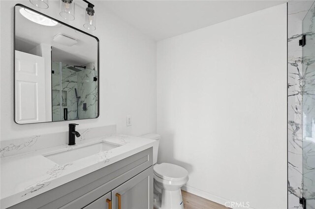 2134 Via Puerta Unit O, Laguna Woods, CA 92637 - full bathroom featuring a marble finish shower, vanity, toilet, baseboards, and wood finished floors