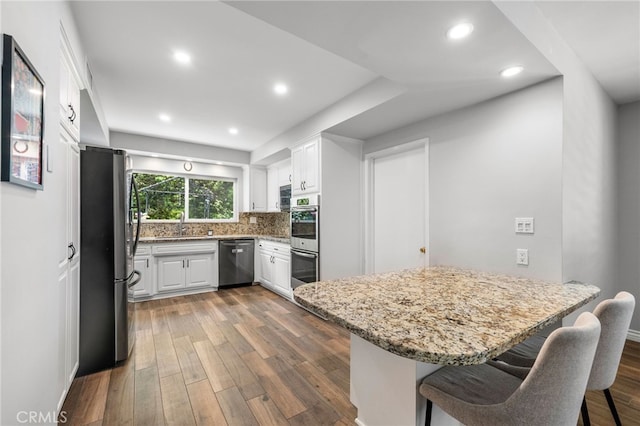 8204 Clemens Ave, West Hills, CA 91304 - kitchen featuring appliances with stainless steel finishes, dark wood-style flooring, white cabinets, light stone counters, and recessed lighting