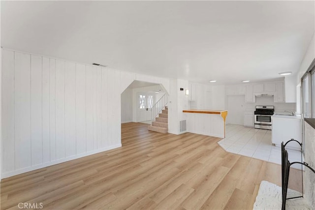 942 E Denwall Dr, Carson, CA 90746 - unfurnished living room with a sink, stairs, light wood-style floors, arched walkways, and healthy amount of natural light
