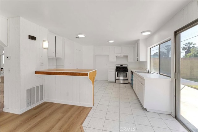 942 E Denwall Dr, Carson, CA 90746 - kitchen with stainless steel gas stove, a sink, a peninsula, light countertops, and white cabinetry