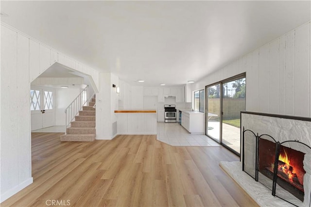 942 E Denwall Dr, Carson, CA 90746 - unfurnished living room featuring a warm lit fireplace, stairs, and light wood-type flooring