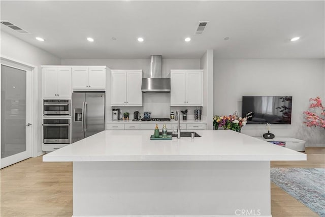 27218 Narrowleaf Willow Ln, Valencia, CA 91381 - kitchen featuring stainless steel appliances, wall chimney range hood, a sink, white cabinetry, and recessed lighting