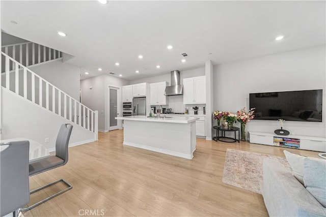 27218 Narrowleaf Willow Ln, Valencia, CA 91381 - kitchen with wall chimney exhaust hood, stainless steel fridge with ice dispenser, open floor plan, white cabinetry, and recessed lighting