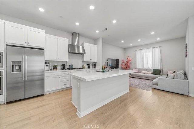 27218 Narrowleaf Willow Ln, Valencia, CA 91381 - kitchen with appliances with stainless steel finishes, wall chimney exhaust hood, a sink, open floor plan, and light countertops