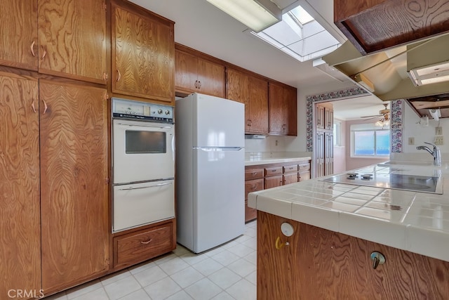 1947 Palacios Dr, San Pedro, CA 90732 - kitchen with white appliances, tile counters, brown cabinets, a sink, and light tile patterned flooring
