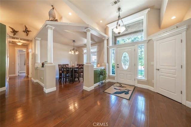 entrance foyer with ornate columns, high vaulted ceiling, wood finished floors, a chandelier, and baseboards