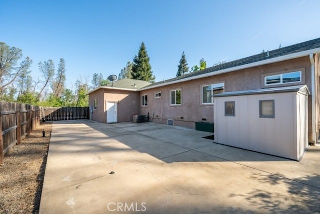 back of house featuring fence, a patio, a gate, and central AC unit