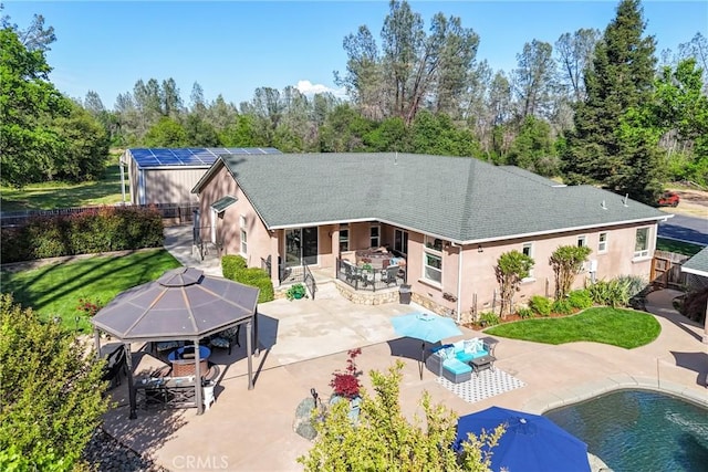 rear view of house featuring a patio, stucco siding, and roof with shingles