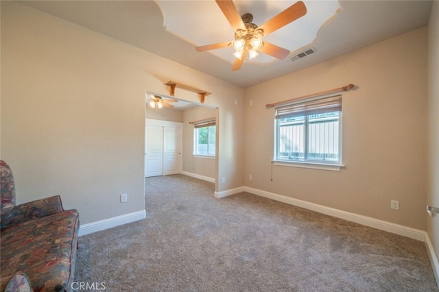 carpeted spare room featuring a ceiling fan and baseboards