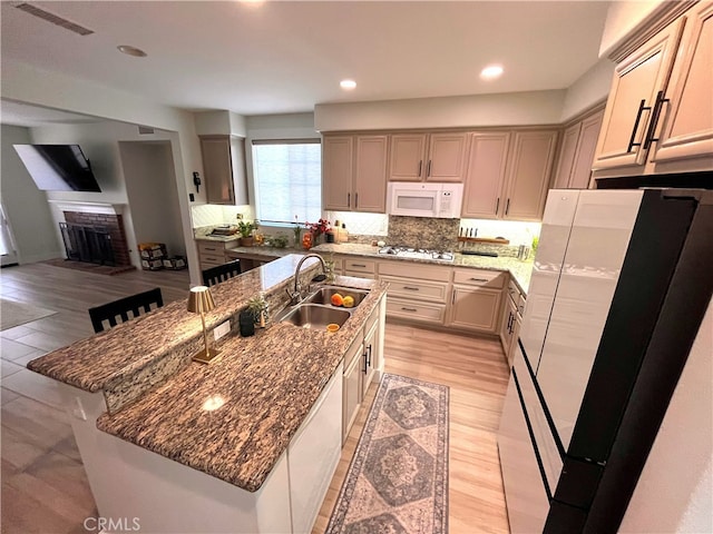 45723 Pheasant Pl, Temecula, CA 92592 - kitchen with white appliances, a sink, decorative backsplash, dark stone counters, and a center island with sink