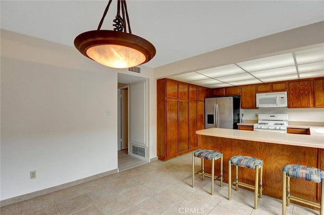 11000 Woodruff Ave Unit 14, Downey, CA 90241 - kitchen featuring white appliances, light countertops, a peninsula, a breakfast bar, and brown cabinetry