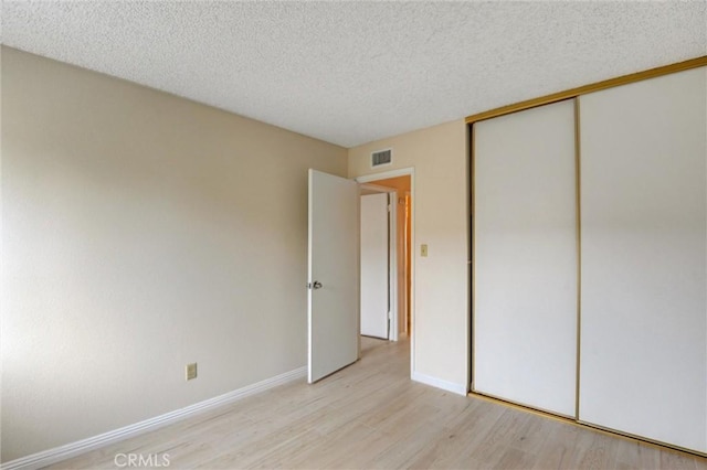 11000 Woodruff Ave Unit 14, Downey, CA 90241 - unfurnished bedroom featuring light wood finished floors, a textured ceiling, a closet, and baseboards