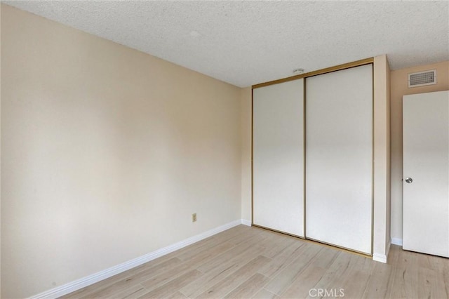 11000 Woodruff Ave Unit 14, Downey, CA 90241 - unfurnished bedroom featuring light wood-style floors, a closet, a textured ceiling, and baseboards