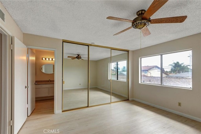 11000 Woodruff Ave Unit 14, Downey, CA 90241 - unfurnished bedroom featuring a textured ceiling, light wood-style floors, connected bathroom, baseboards, and a ceiling fan