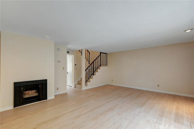 11000 Woodruff Ave Unit 14, Downey, CA 90241 - unfurnished living room featuring light wood-type flooring, stairway, a fireplace, and baseboards