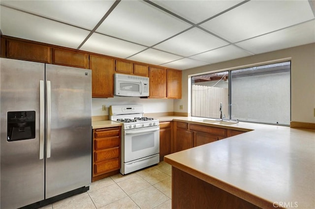 11000 Woodruff Ave Unit 14, Downey, CA 90241 - kitchen with white appliances, a sink, brown cabinetry, light countertops, and light tile patterned floors