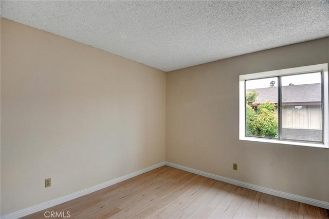 11000 Woodruff Ave Unit 14, Downey, CA 90241 - spare room featuring light wood-style flooring, baseboards, and a textured ceiling