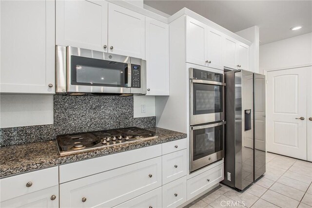 1004 Violet Ct, Calimesa, CA 92320 - kitchen featuring stainless steel appliances, white cabinets, light tile patterned flooring, backsplash, and dark stone counters