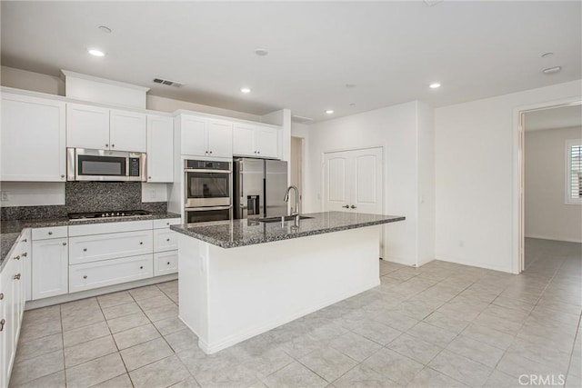 1004 Violet Ct, Calimesa, CA 92320 - kitchen with appliances with stainless steel finishes, a center island with sink, dark stone countertops, white cabinets, and backsplash