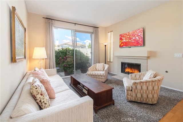 living area with a tiled fireplace, wood finished floors, and baseboards