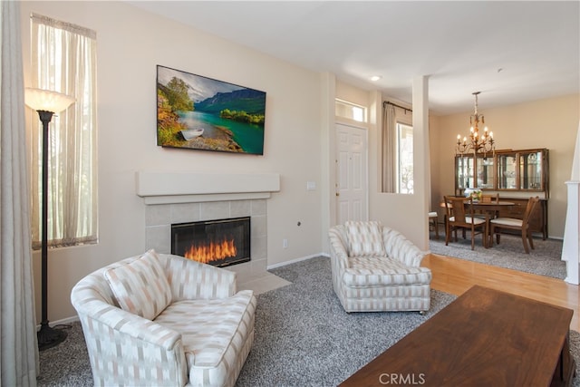 living area with a chandelier, a tile fireplace, baseboards, and wood finished floors