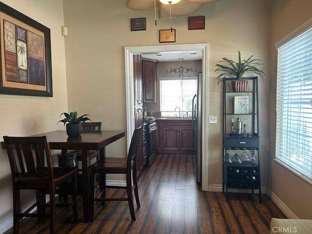 dining room featuring dark wood-style floors, a ceiling fan, and baseboards