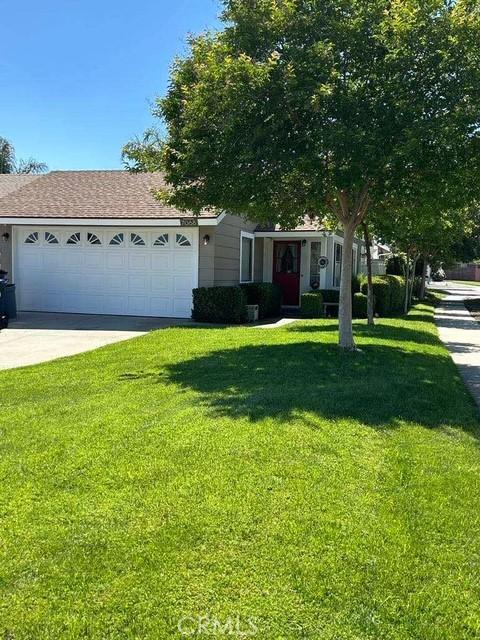 view of front of home with a garage, a front yard, concrete driveway, and a shingled roof