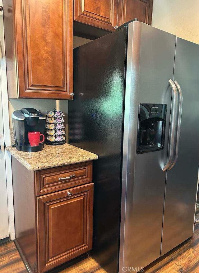 kitchen featuring stainless steel fridge with ice dispenser, wood finished floors, and light stone counters