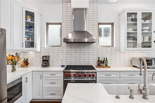 1715 Reed St, Redondo Beach, CA 90278 - kitchen with wall chimney exhaust hood, stainless steel appliances, tasteful backsplash, white cabinets, and glass insert cabinets