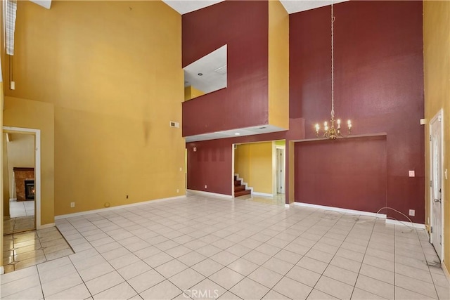 unfurnished living room featuring a high ceiling, a chandelier, baseboards, tile patterned flooring, and stairs