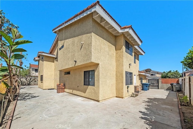 back of property with stucco siding, a patio area, a fenced backyard, and a gate