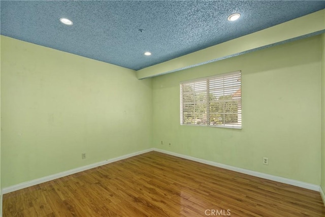 spare room with baseboards, wood finished floors, recessed lighting, and a textured ceiling