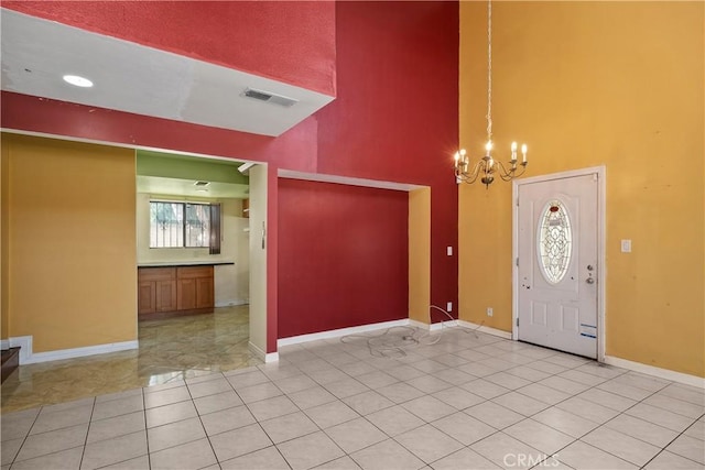 entryway with a high ceiling, a chandelier, light tile patterned floors, and baseboards