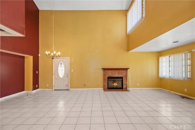 foyer featuring a high ceiling, a chandelier, baseboards, a tiled fireplace, and light tile patterned floors