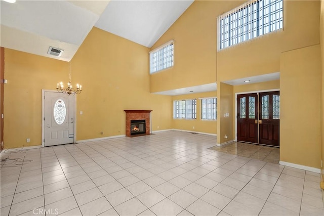 entrance foyer featuring high vaulted ceiling, a chandelier, a fireplace with flush hearth, baseboards, and healthy amount of natural light